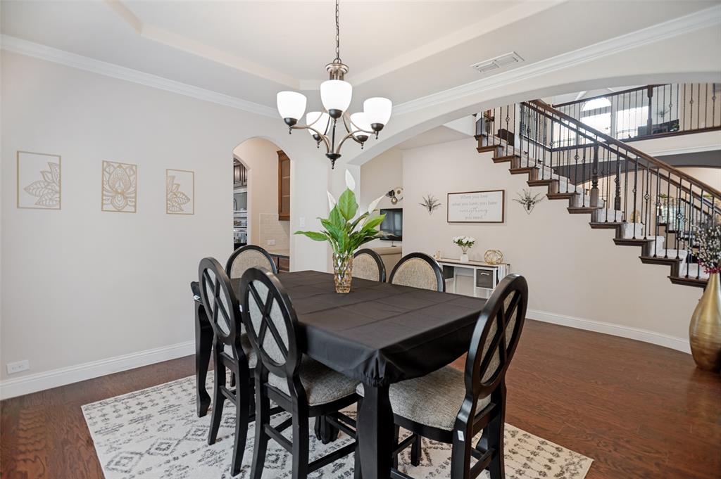 413 Frontier Court Midlothian, TX 76065 - Photo 5 of 26 Formal dining area featuring rich wood-finish flooring, a tray ceiling, and a traditional chandelier
