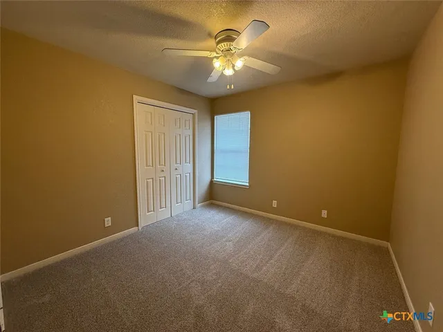 a view of an empty room with a chandelier fan