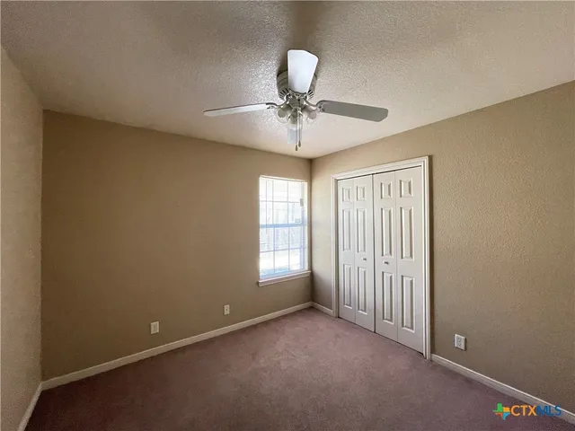 an empty room with windows and fan