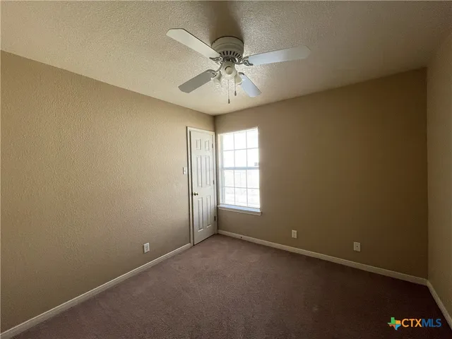 an empty room with a window and a fan