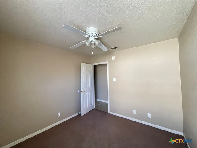 an empty room with a ceiling fan and a window