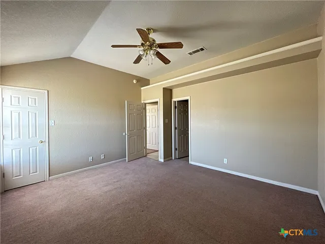 a view of an empty room and chandelier fan