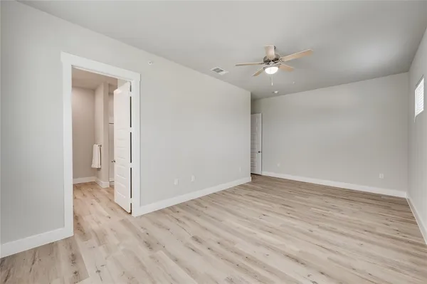 an empty room with wooden floor ceiling fan and window