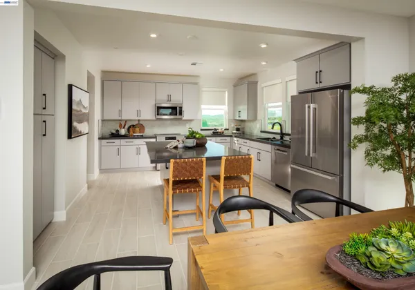 a kitchen with stainless steel appliances kitchen island granite countertop a refrigerator a stove a sink dishwasher and a dining table with wooden floor