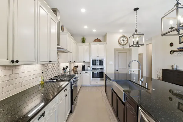 a kitchen with granite countertop a sink stove and cabinets