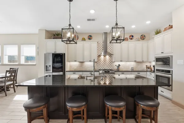a kitchen with granite countertop a counter space chairs stainless steel appliances and cabinets