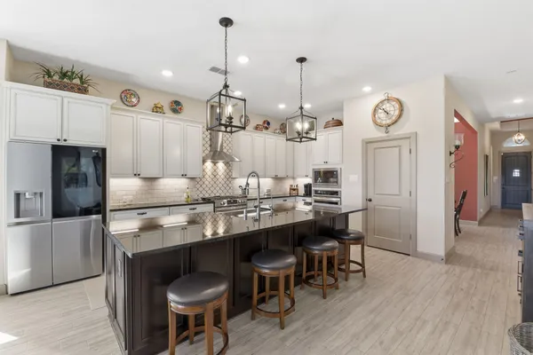 a kitchen with kitchen island stainless steel appliances a dining table chairs sink and cabinets