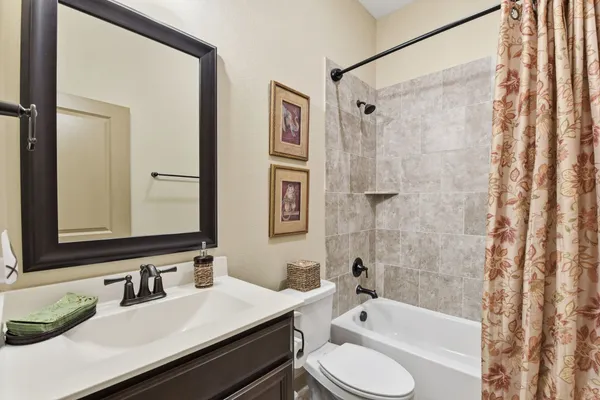 a bathroom with a granite countertop sink toilet a mirror a bathtub and shower