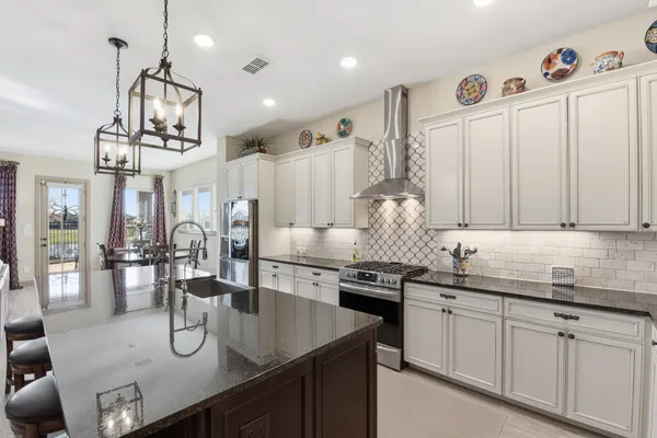 a kitchen with stainless steel appliances granite countertop a sink dishwasher and white cabinets with wooden floor