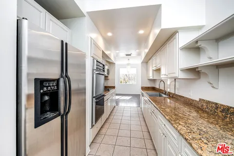 a kitchen with stainless steel appliances granite countertop a refrigerator and a sink