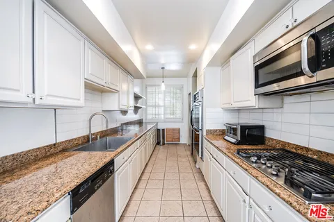 a large kitchen with granite countertop a stove and a sink