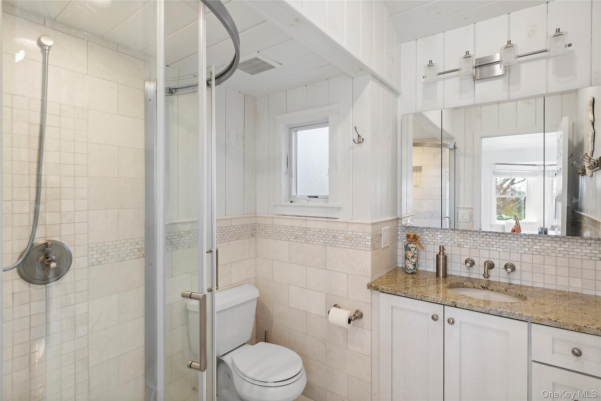 67 North Road, Unit A Hampton Bays, NY 11946 - Photo 9 of 17 Full bathroom with a shower stall, vanity, tile walls, toilet, and healthy amount of natural light
