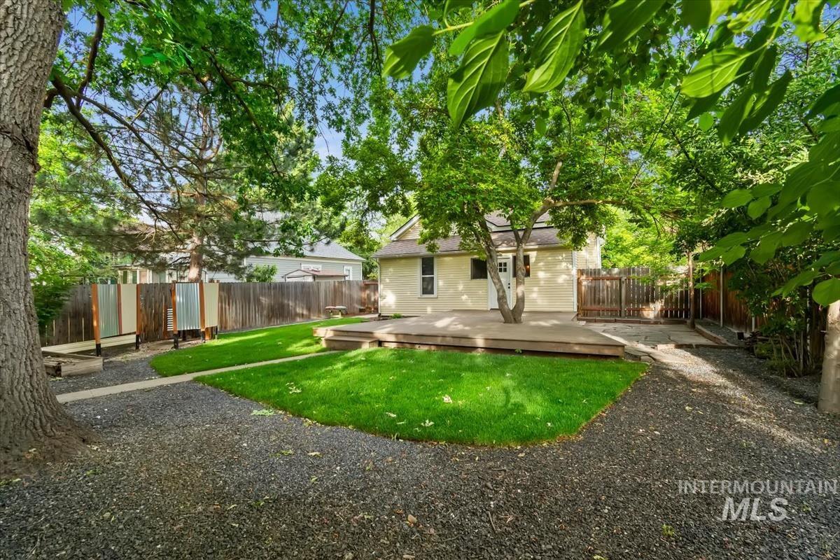 910 North 16th Street Boise, ID 83702 - Photo 36 of 47 Expansive backyard featuring a manicured lawn, a large wooden deck, mature trees, and a gravel pathway