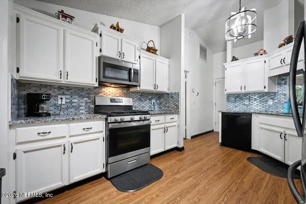 a kitchen with stainless steel appliances granite countertop a stove a sink and a microwave