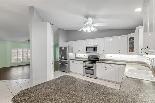a large kitchen with cabinets stainless steel appliances a sink and a stove