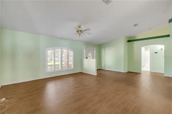 a view of an empty room with a window and wooden floor
