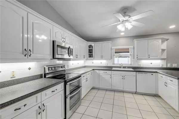 a kitchen with granite countertop white cabinets white stainless steel appliances with a sink and dishwasher