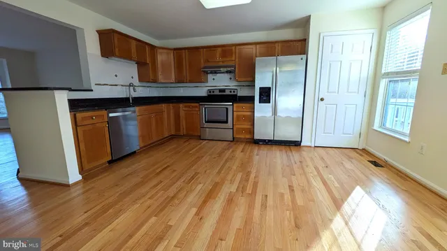 a kitchen with stainless steel appliances granite countertop a refrigerator a sink and wooden cabinets