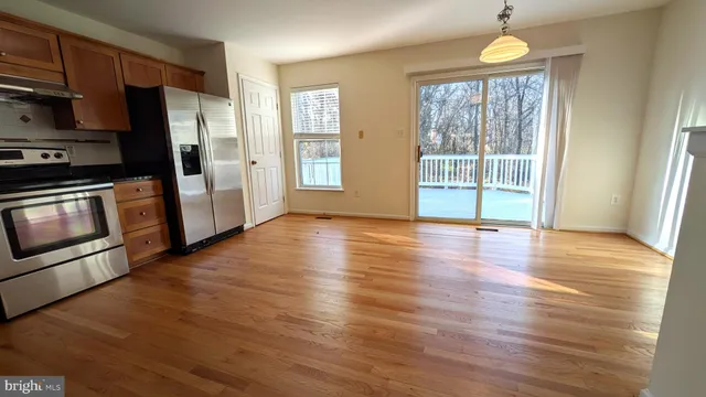 a view of a kitchen with wooden floor electronic appliances and windows