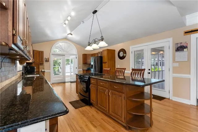 a kitchen with stainless steel appliances granite countertop a refrigerator a stove and a microwave with wooden floor