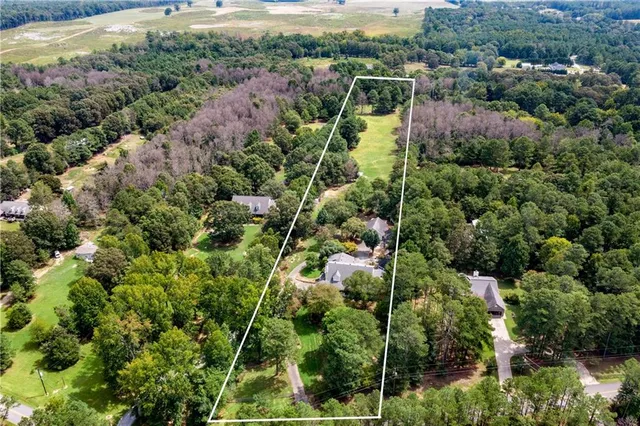 an aerial view of residential houses with outdoor space and trees