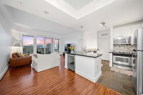a kitchen with stainless steel appliances white cabinets granite counter tops and a wooden floors