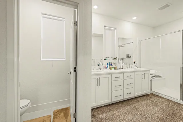 a bathroom with a double vanity sink toilet and shower