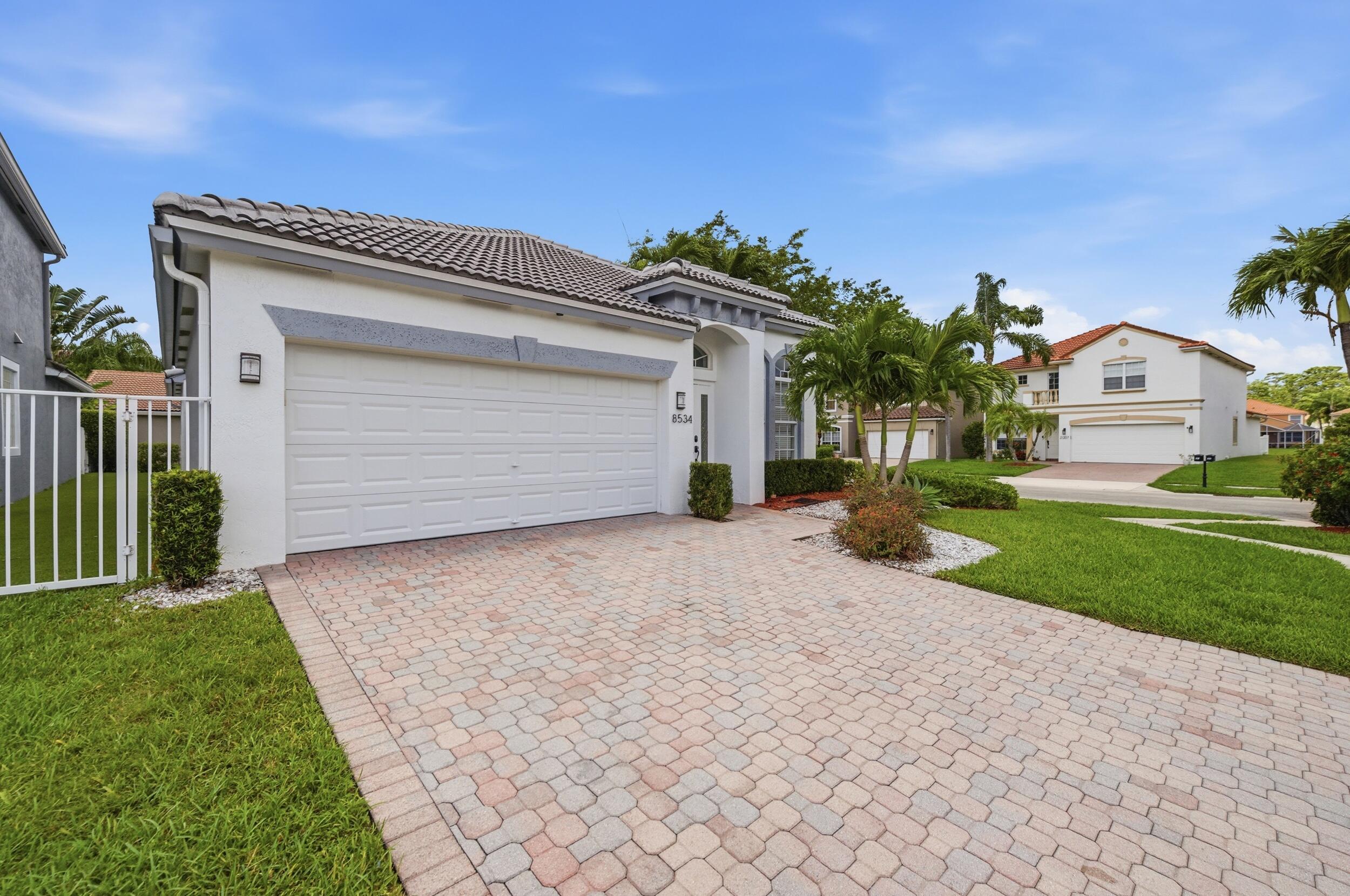 8534 Vía D Oro Boca Raton, FL 33433 - Photo 2 of 34 a view of a house with a yard and a garage