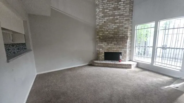 a view of an empty room with a fireplace and a window