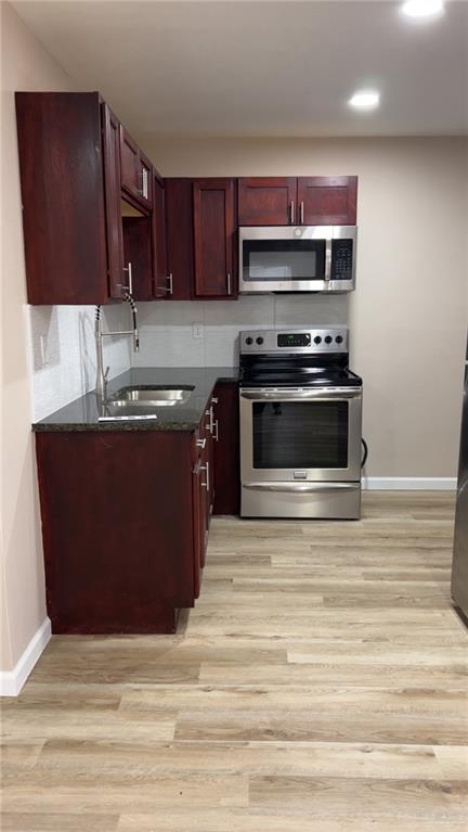 106 North 17th Street, Unit 23 Donna, TX 78537 - Photo 2 of 5 a kitchen with a sink and a stove with wooden cabinets