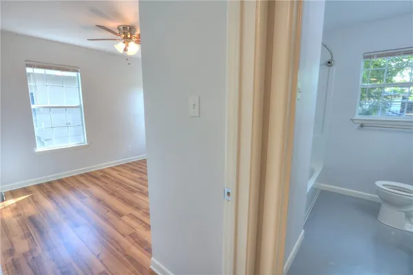 a view of a hallway with wooden floor and a bathroom