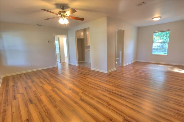 a view of an empty room with window and wooden floor