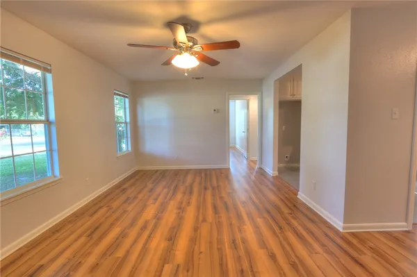 a view of an empty room with wooden floor and a window
