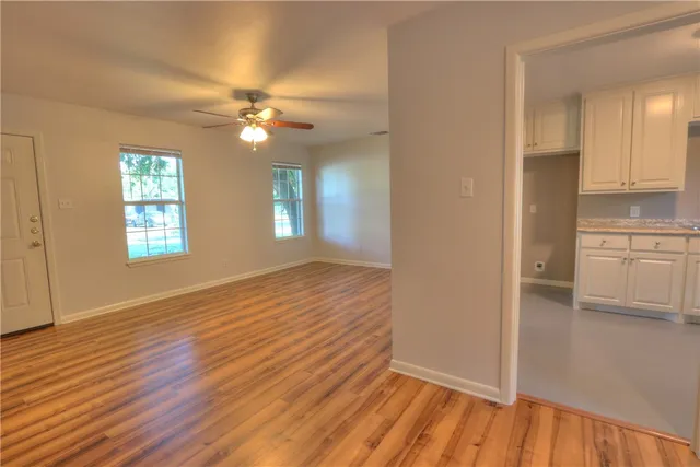 a view of an empty room with window and wooden floor