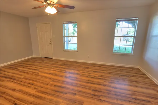 a view of an empty room with wooden floor and a window