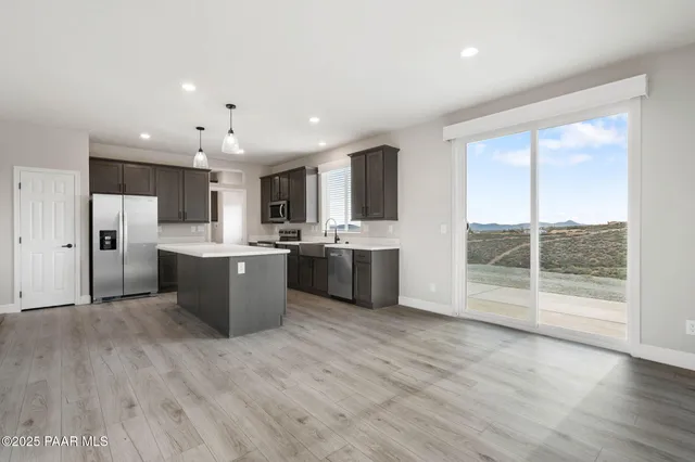 a view of kitchen with stainless steel appliances kitchen island wooden cabinets and window