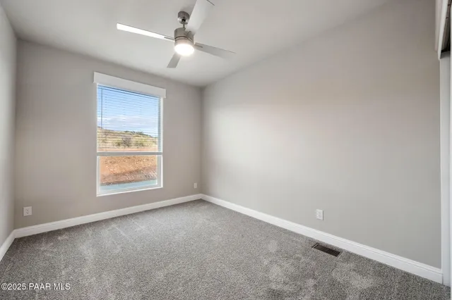 an empty room with a window and a fan