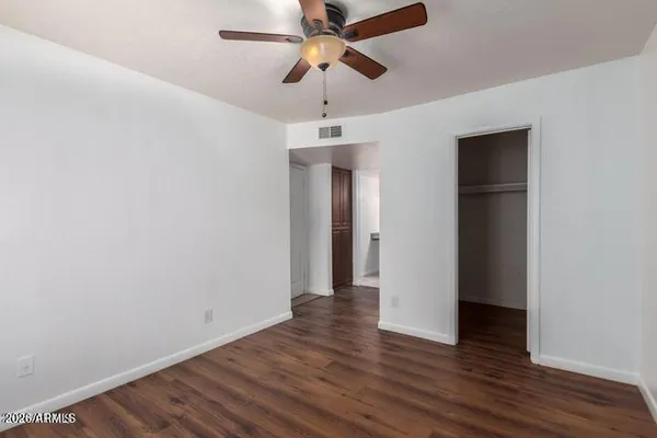 a view of a hallway with wooden floor and a chandelier fan