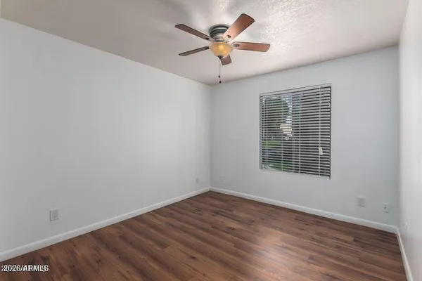 a view of an empty room with a window and wooden floor