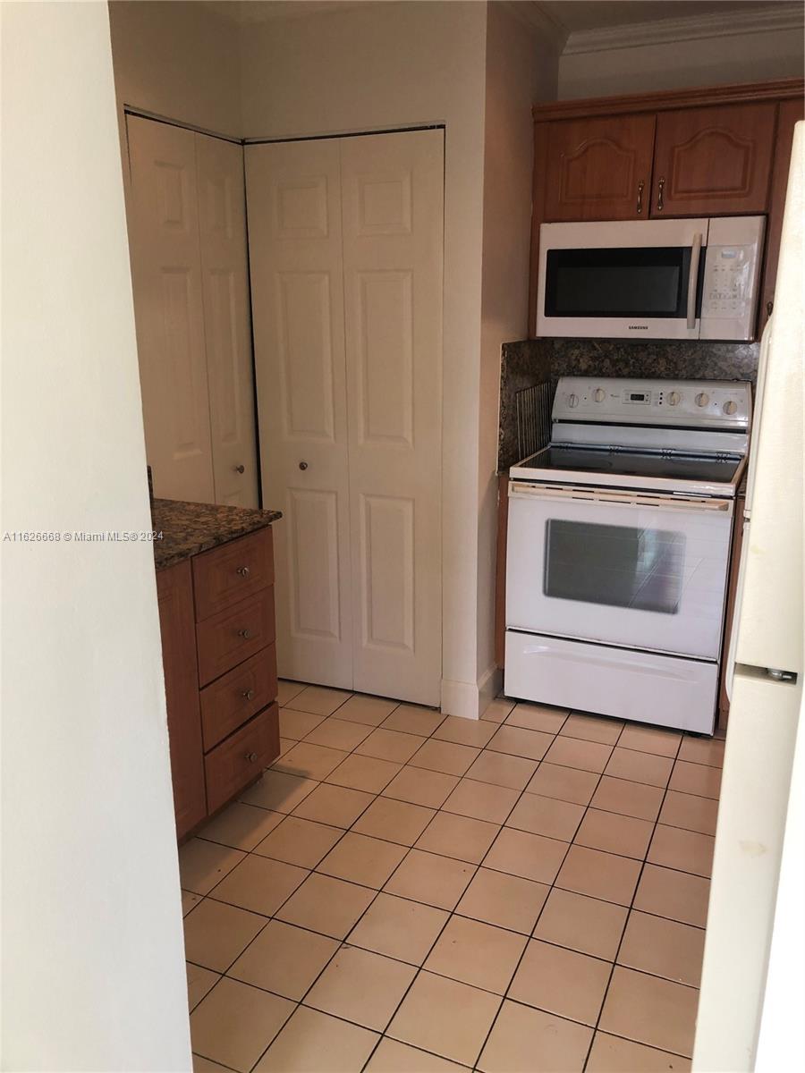 6901 Southwest 129th Avenue, Unit 5 Miami, FL 33183 - Photo 10 of 19 a kitchen with granite countertop a stove a microwave and a refrigerator
