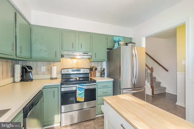 a kitchen with stainless steel appliances granite countertop a refrigerator a stove and a sink with wooden floor