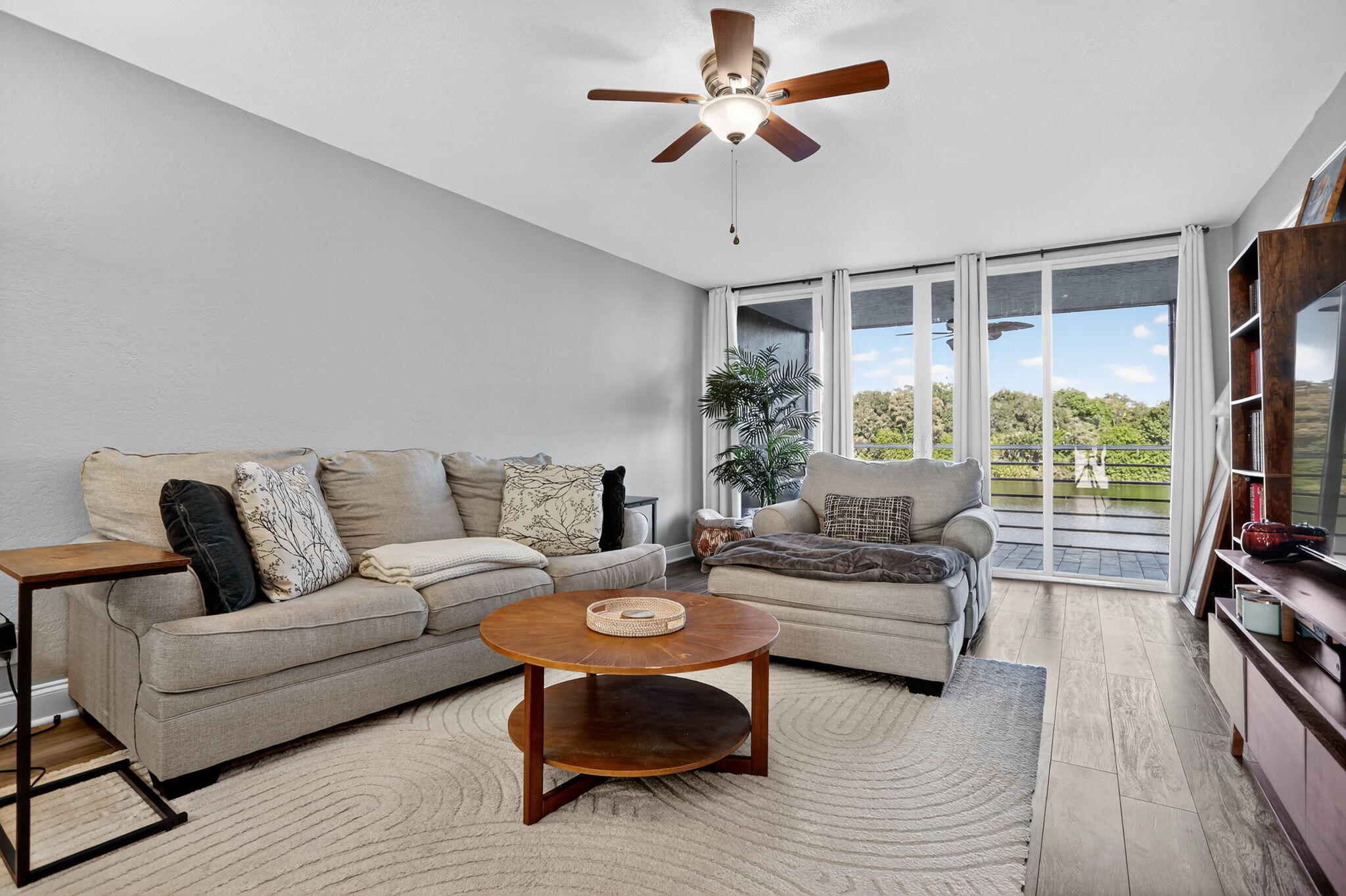 a living room with furniture a flat screen tv and a large window
