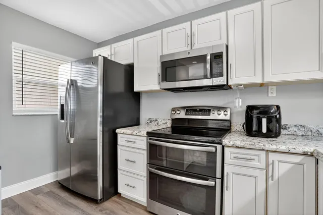 a kitchen with stainless steel appliances granite countertop white cabinets and a stove top oven