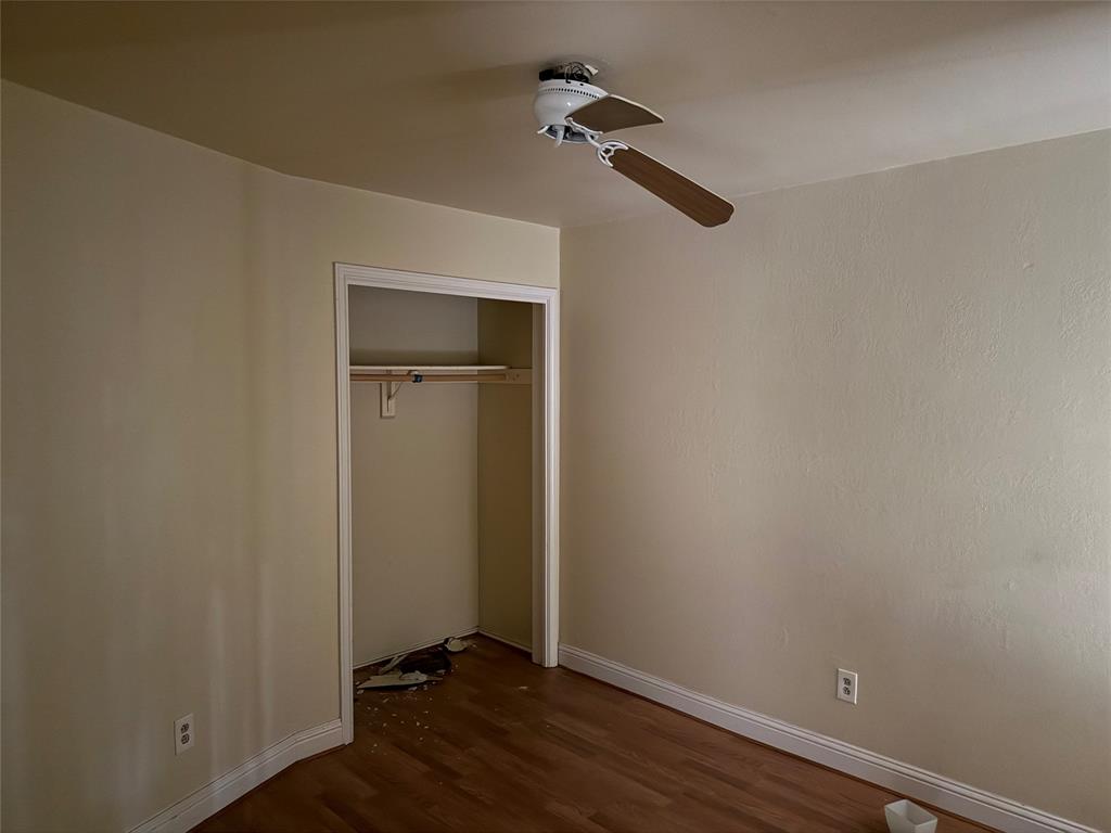10823 Addie Road Dallas, TX 75217 - Photo 13 of 20 Wood-finish flooring with white trim, ceiling fan with wood-finish blades, and an open closet with a single hanging rod