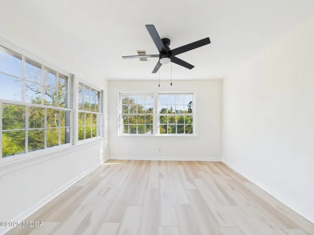 a view of empty room with wooden floor and fan