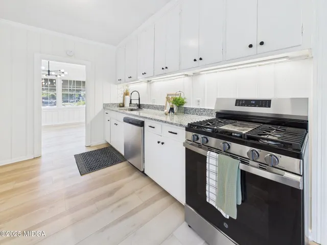 a kitchen with granite countertop white cabinets and stainless steel appliances