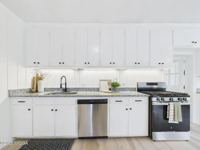 a kitchen with granite countertop white cabinets and stainless steel appliances
