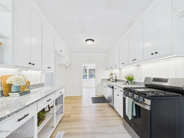 a kitchen with granite countertop white cabinets and a refrigerator