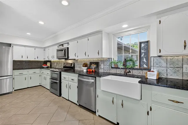 a kitchen that has a lot of white cabinets and stainless steel appliances