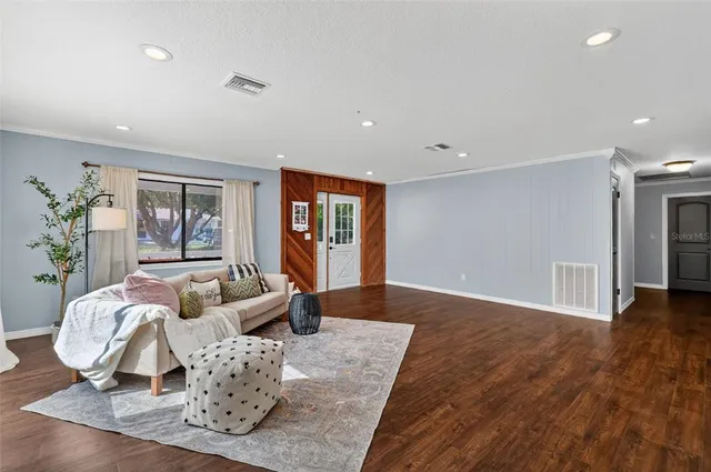a living room with furniture two window and wooden floor